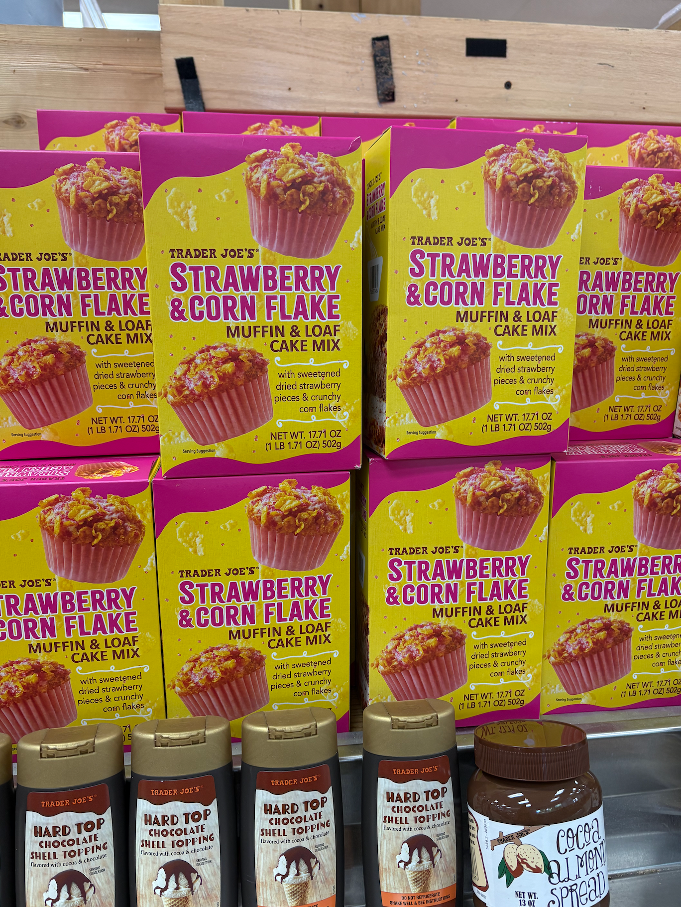 Boxes of Trader Joe's Strawberry &amp;amp; Corn Flake Muffin Mix on display above various bottles of syrup
