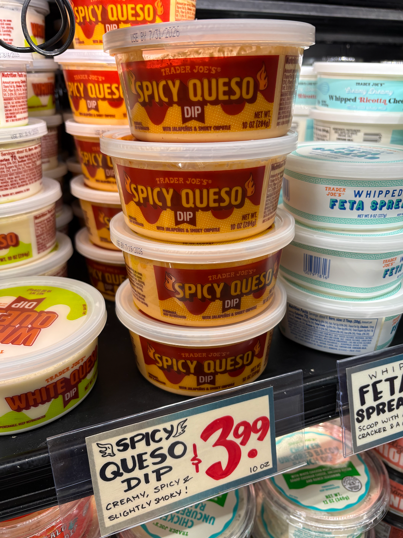 Spicy Queso Dip on a supermarket shelf, priced at $3.99 for 10 oz, labeled "creamy, spicy, &amp;amp; slightly smoky."