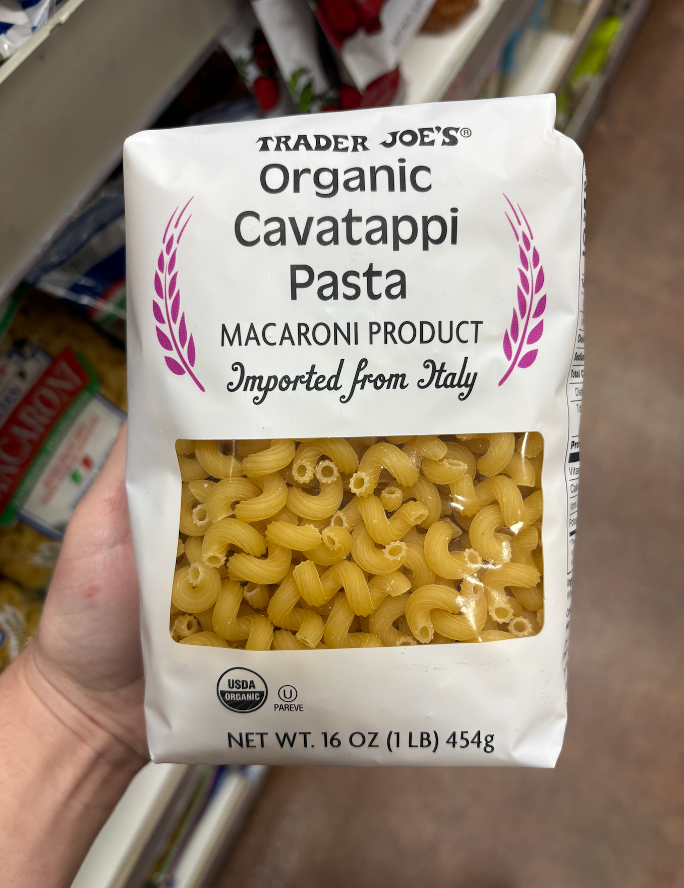 Hand holding a 16 oz package of Trader Joe’s organic cavatappi pasta, imported from Italy