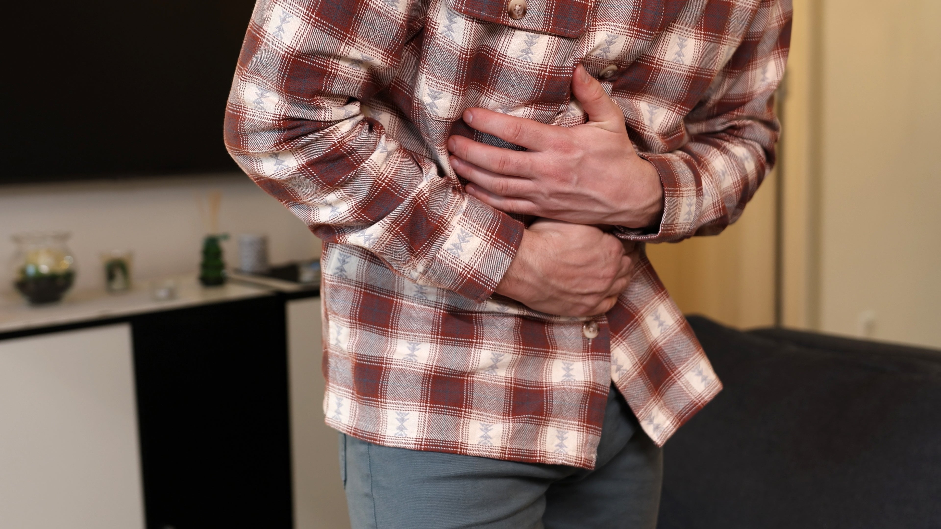 Person clutching their stomach, appearing to acquisition   discomfort oregon  pain, lasting  successful  a surviving  country   setting