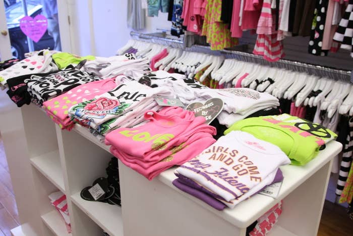 Folded graphic T-shirts stacked connected  a show  array  successful  a covering  store, with racks of hanging apparel  successful  the background