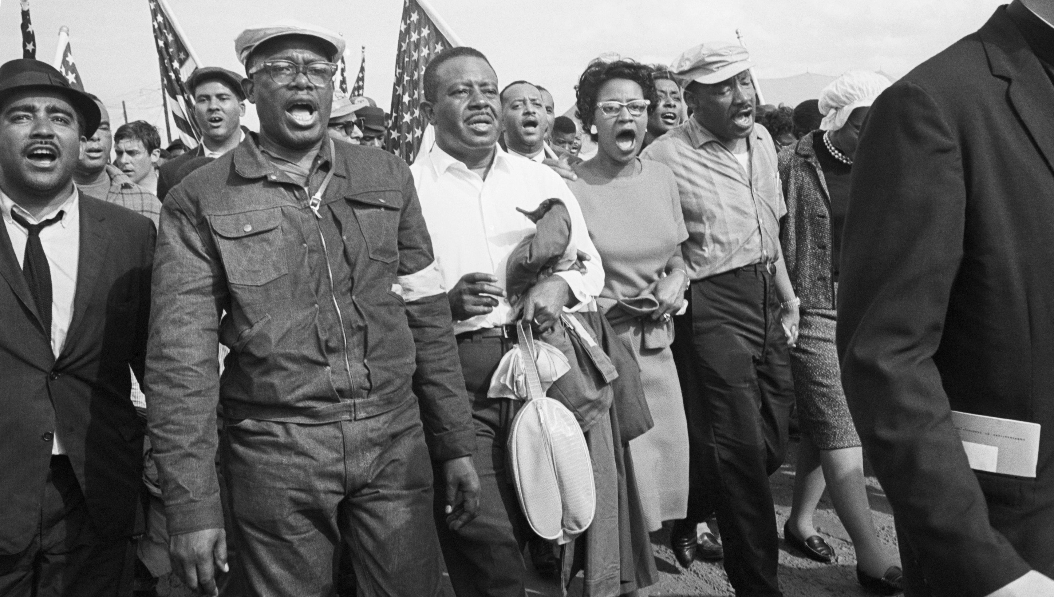 A radical of men and women march together, passionately singing oregon chanting, successful a historical civilian rights protest