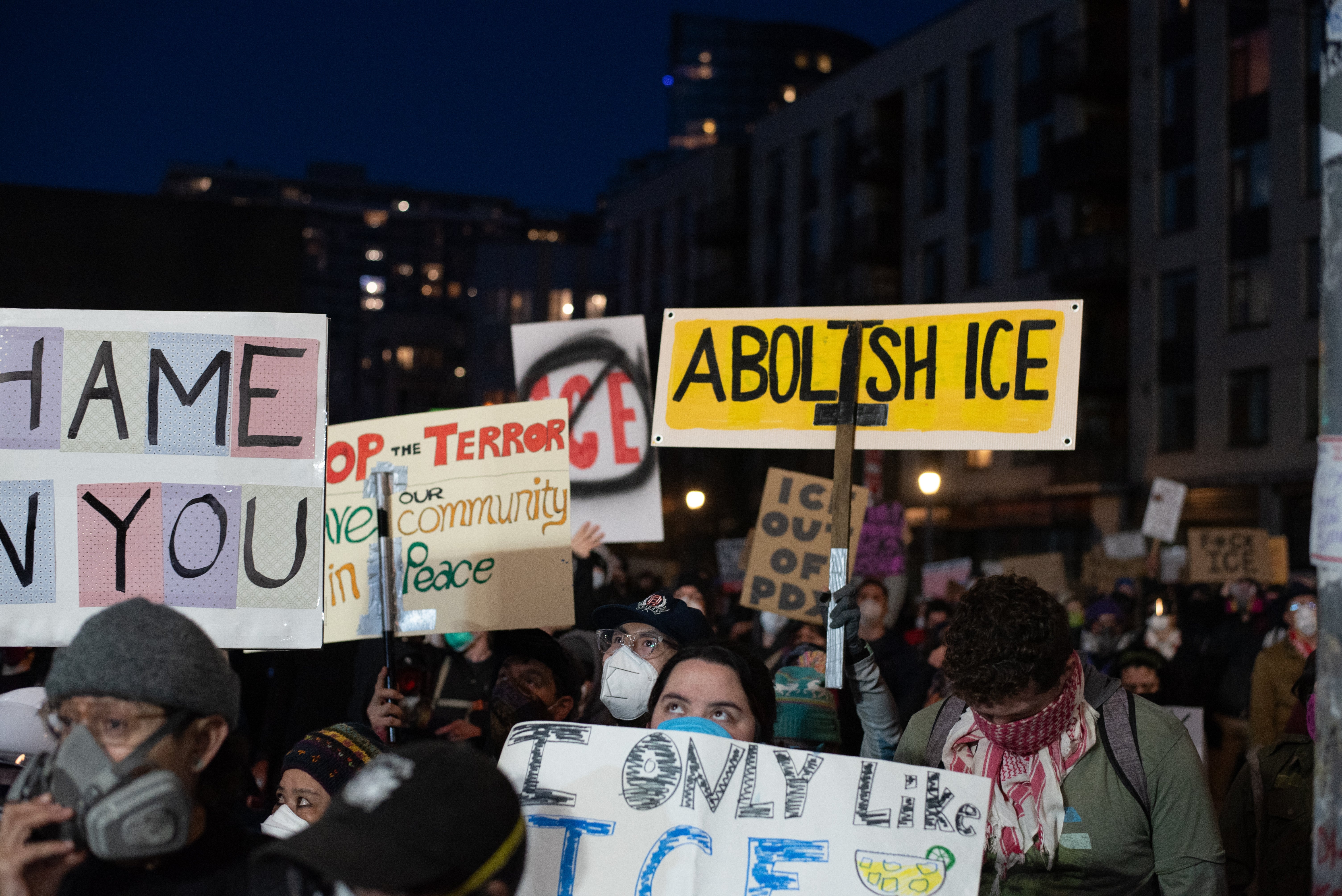 Protesters holding signs astatine a rally, including messages similar "Abolish ICE" and "Stop the terror," advocating for alteration and assemblage peace