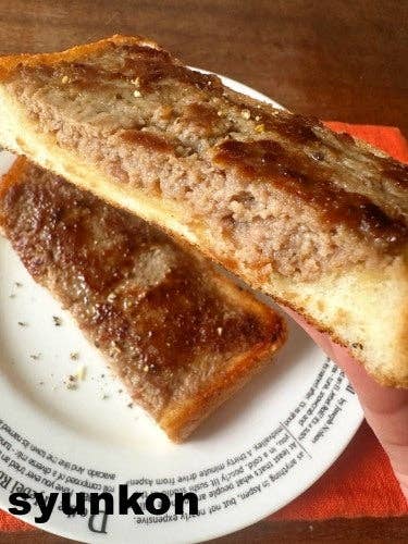 皿にパンに乗せたひき肉トーストがあり、テーブルに置かれています。