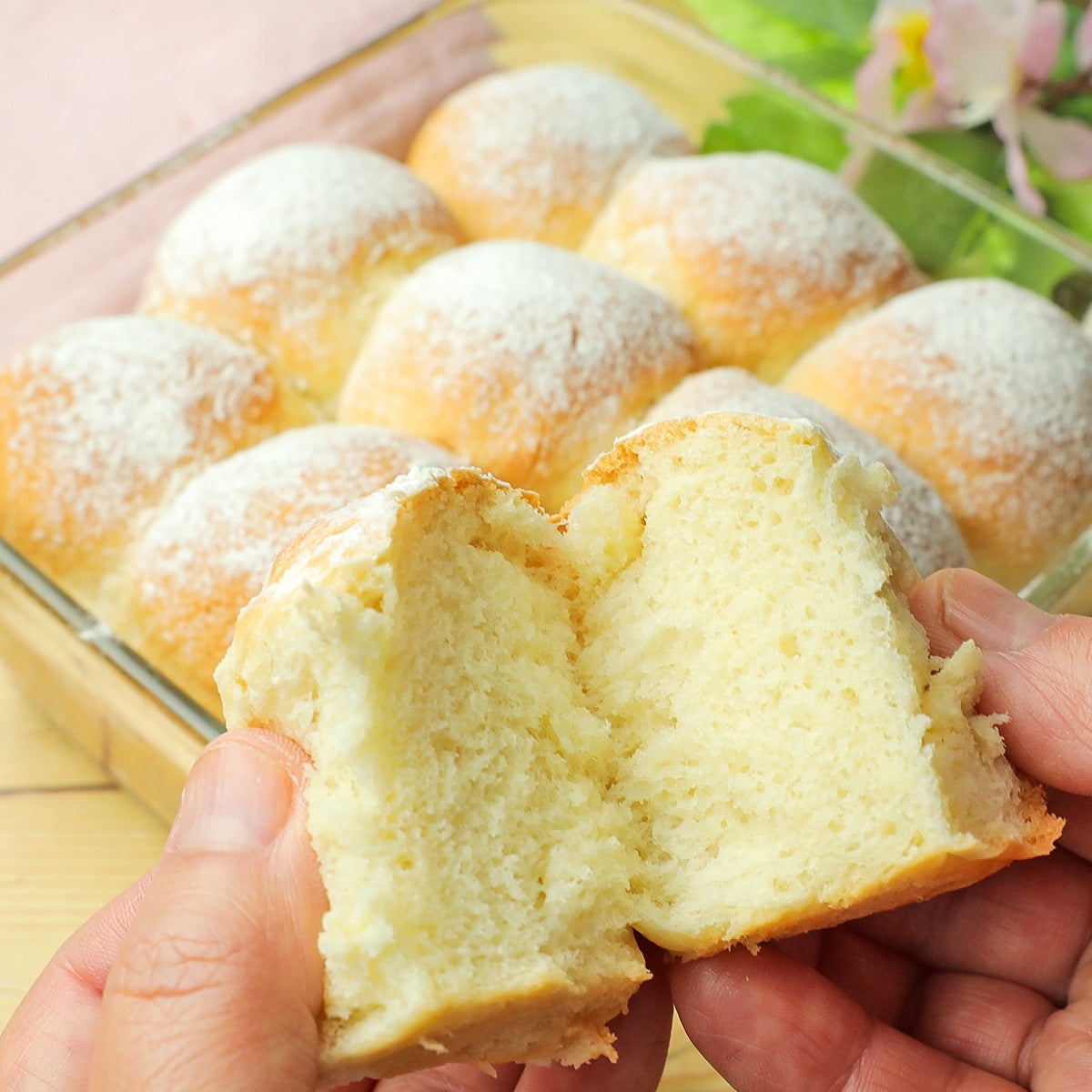 手で割られた焼きたての柔らかいパン。背景にはガラスの容器に入った他のパンが見える。