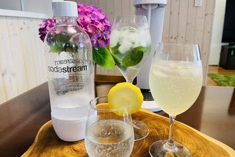 ソーダストリームボトルと3種類の炭酸ドリンクが卓上に並び、紫陽花が背景にある様子
