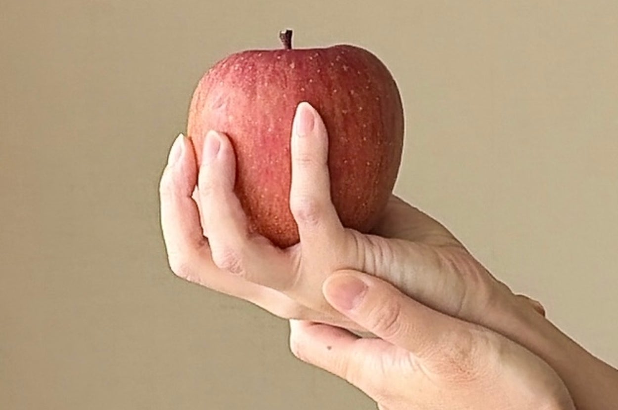 手に持たれた一つのリンゴ。