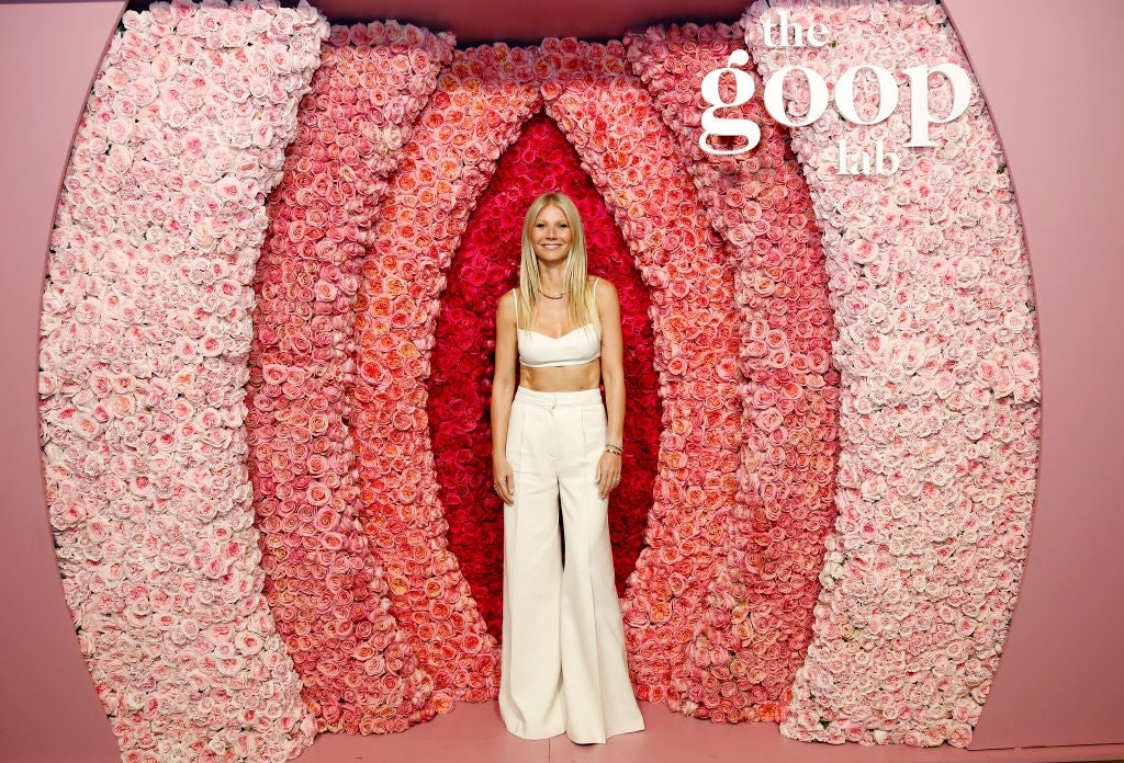 Gwyneth Paltrow stands in front of floral backdrop that looks like a vagina with "The Goop Lab" logo