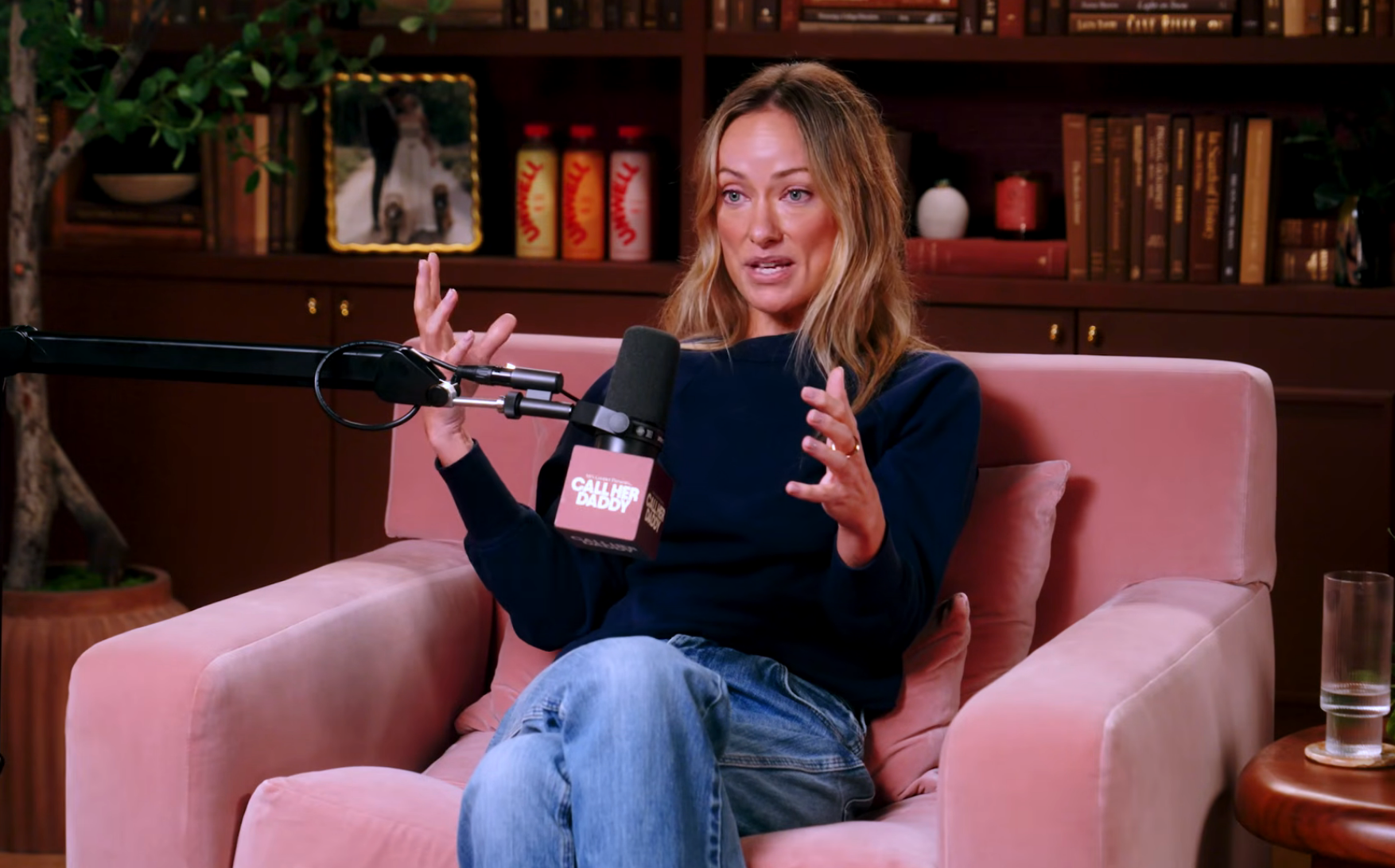 Person sitting successful  a cozy armchair, speaking into a microphone during a podcast oregon  interview. Bookshelves successful  the background