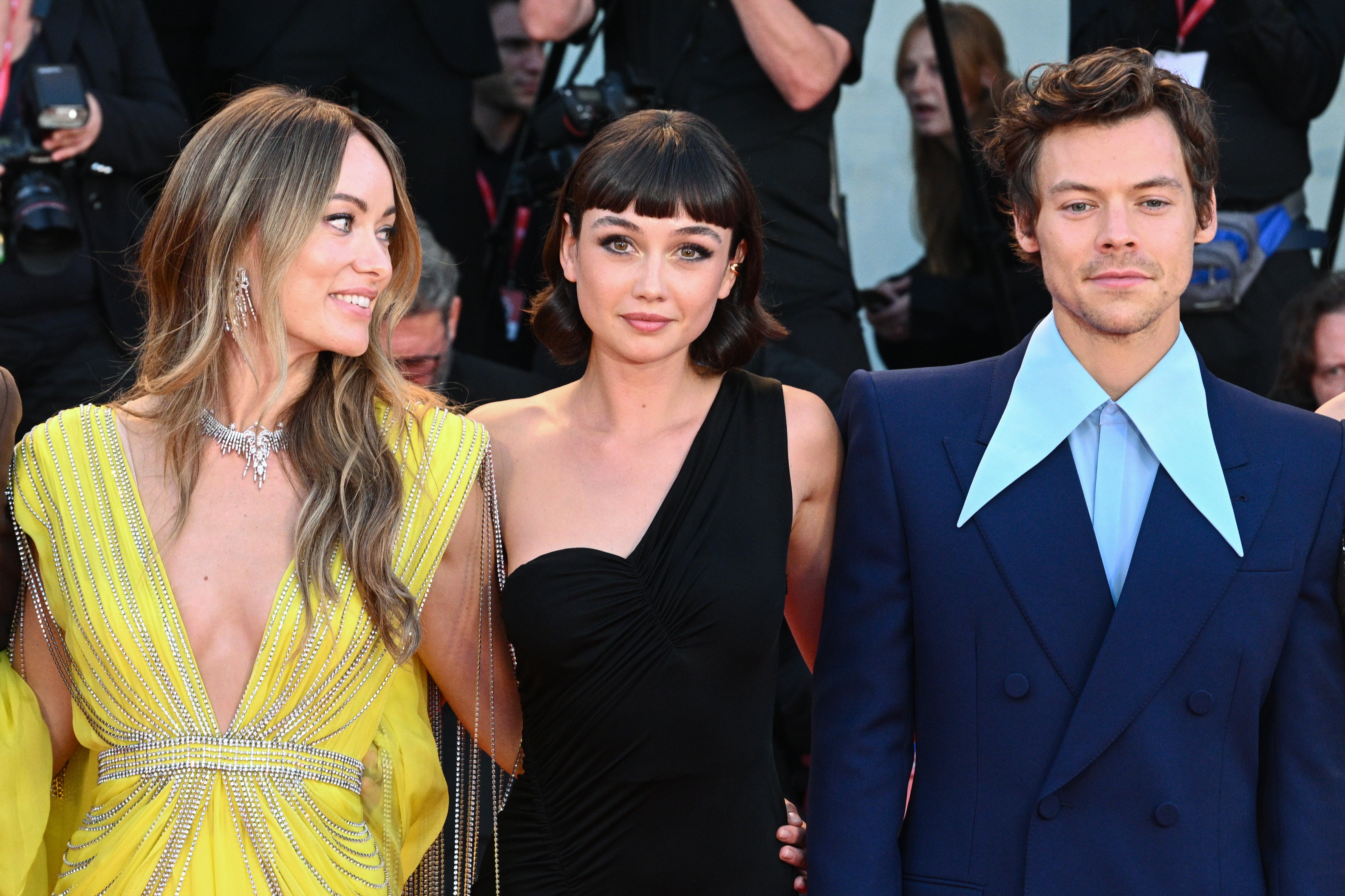 Three radical   airs  connected  a reddish  carpet event. The idiosyncratic   connected  the near  wears a flowing gown, the halfway  idiosyncratic   wears a one-shoulder dress, and the idiosyncratic   connected  the close    wears a suit   with a wide   collar