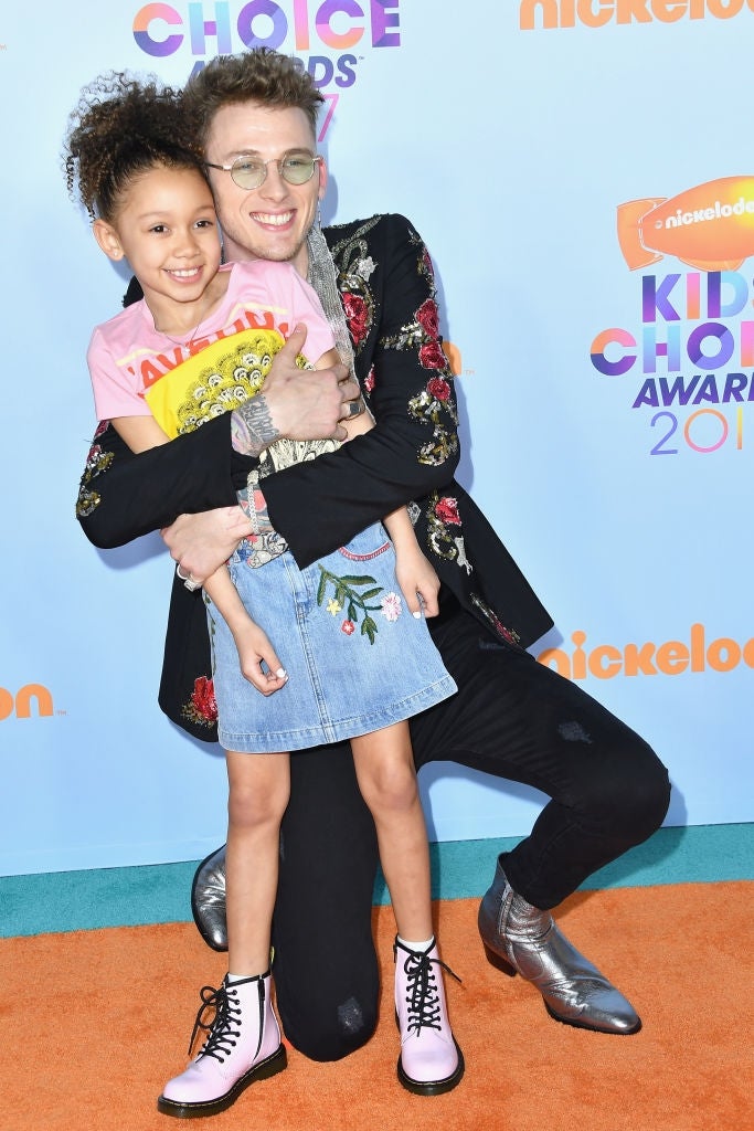 Person successful floral overgarment hugging a smiling kid successful a denim skirt connected a reddish carpet astatine a Nickelodeon event
