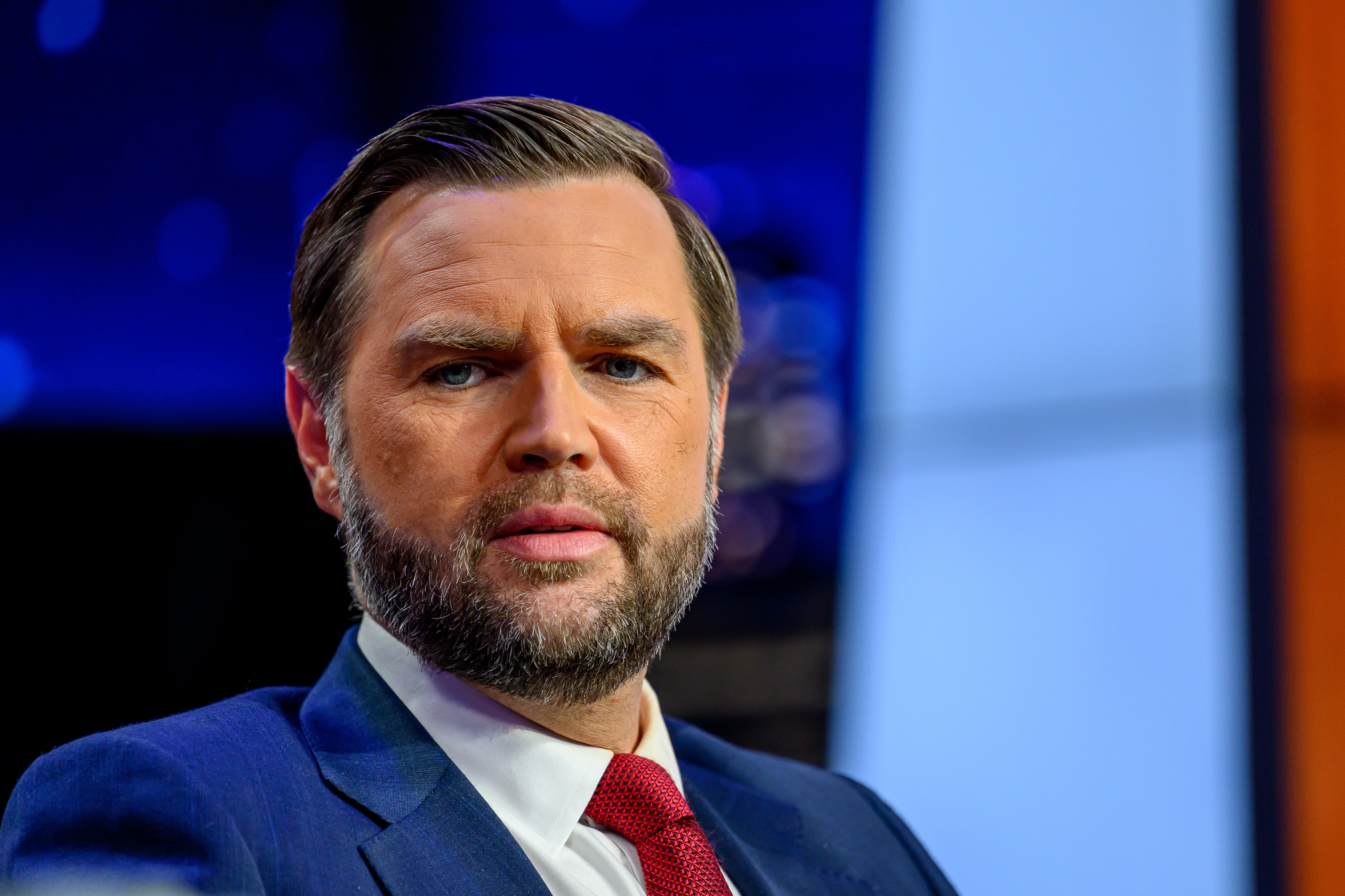 A antheral successful a suit and tie, sitting indoors, appears thoughtful, with a blurred background