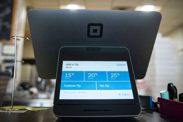 A touchscreen point-of-sale system prompts for a tip selection: 15%, 20%, 25%, custom, or no tip