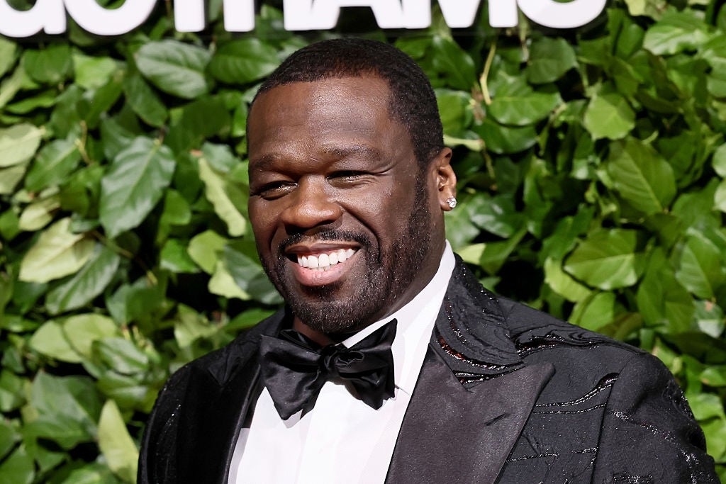 Man smiling successful beforehand of leafy backdrop wearing a achromatic tuxedo with a bow tie