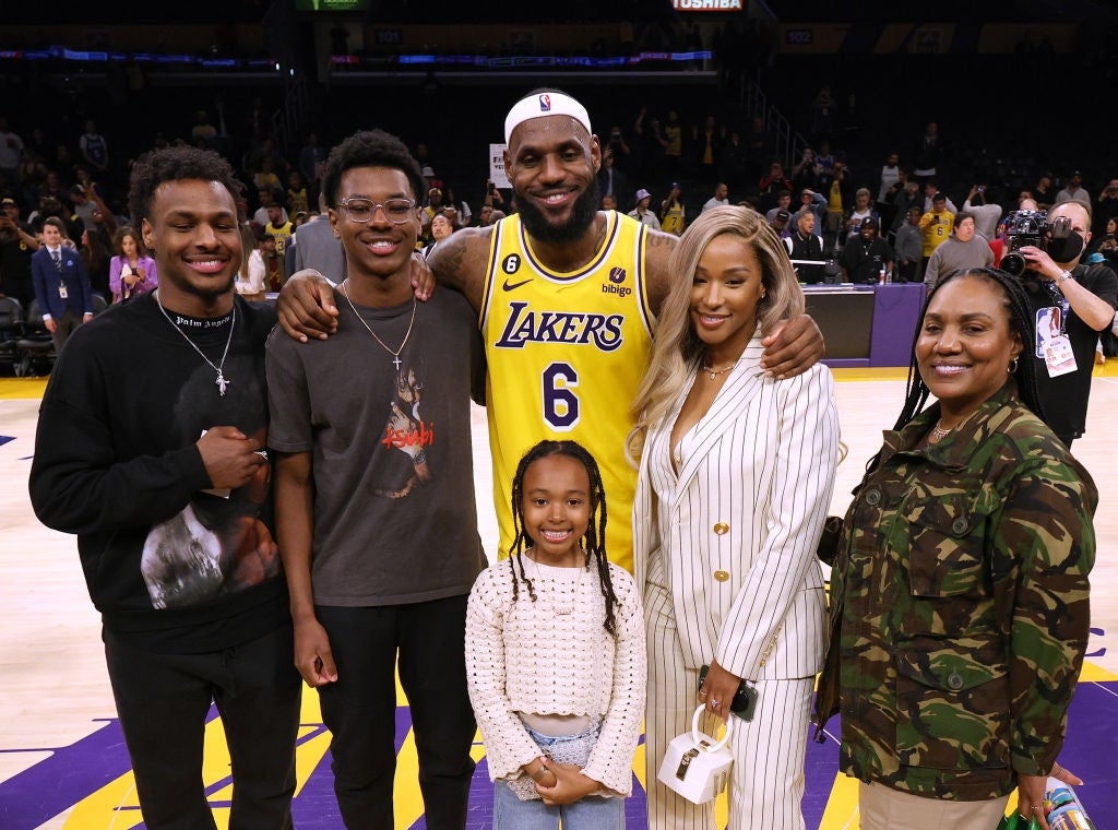Group of radical posing connected a hoops court; 1 wears a Lakers jersey, different successful a striped suit, others successful casual attire