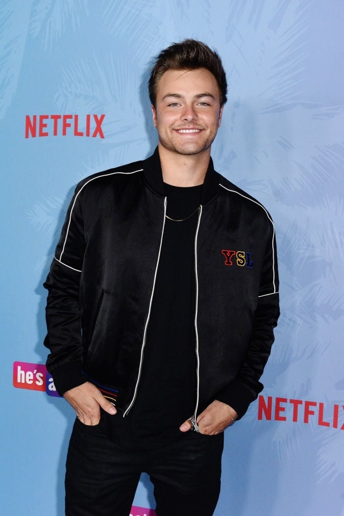 A idiosyncratic smiling astatine a Netflix event, wearing a casual achromatic overgarment implicit a t-shirt