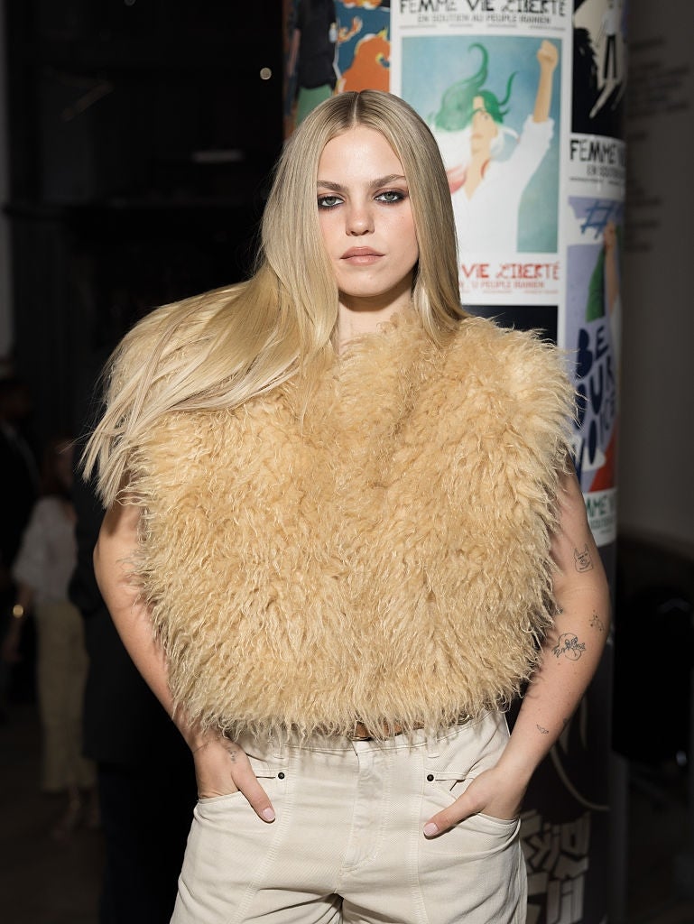 Person successful  a fluffy apical  poses confidently with hands successful  pockets astatine  an event. Stylish quality  with minimal inheritance  details