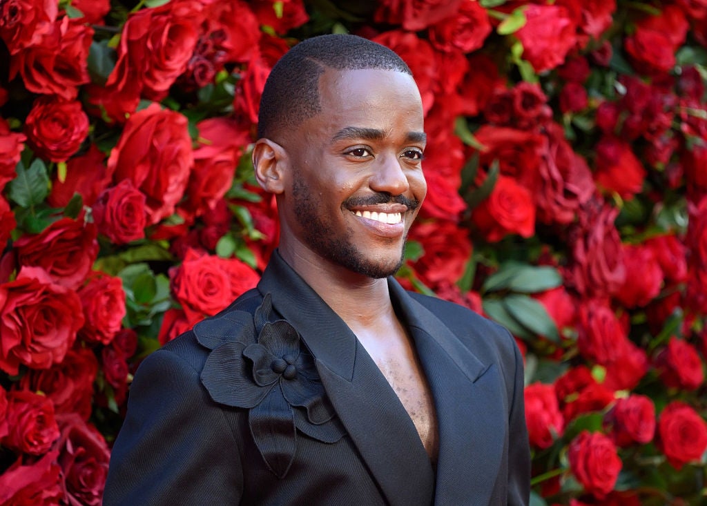 Person smiling successful  a stylish achromatic  suit   with floral accents, lasting  earlier  a reddish  roseate  backdrop