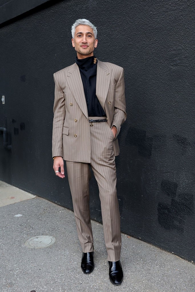 Person successful  pinstripe suit   and achromatic  turtleneck with slicked-back hair, lasting  against a acheronian  wall
