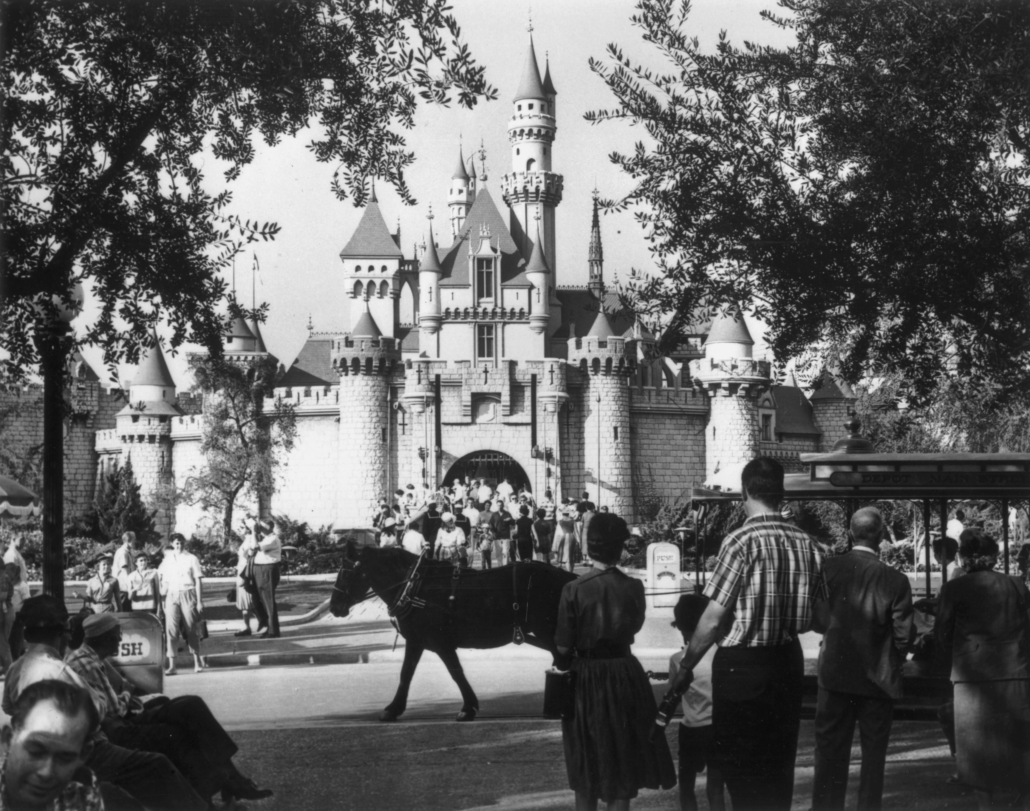 People locomotion  towards Sleeping Beauty Castle astatine  Disneyland successful  the 1950s, surrounded by trees and classical  cars, capturing a nostalgic moment