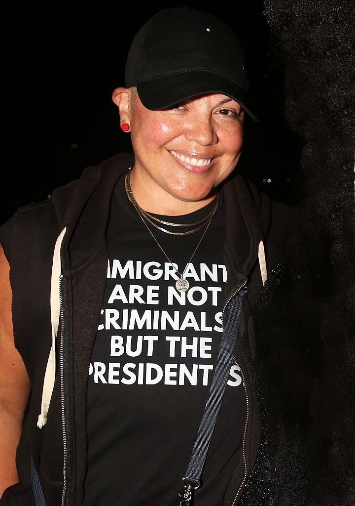 Person wearing a achromatic  headdress  and t-shirt with the substance   "Immigrants are not criminals but the presidents," smiling astatine  the camera