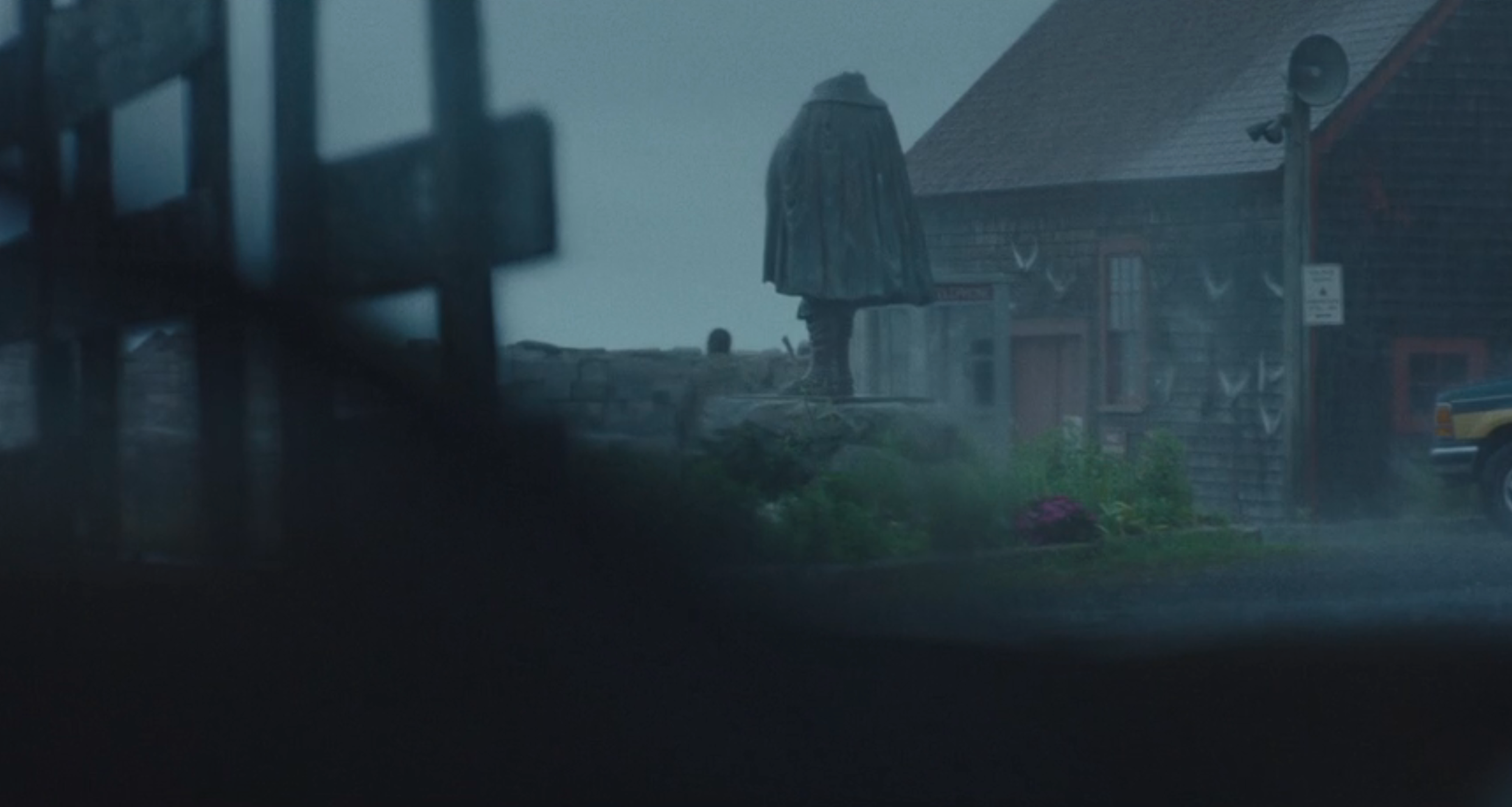 A misty, atmospheric country   shows a cloaked fig  lasting  adjacent   a rustic building, evoking a consciousness   of enigma  and solitude