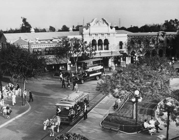 Vintage photograph  of Main Street, Disneyland, with horse-drawn trolley and aboriginal  1900s vehicles. Guests and unit   capable    the thoroughfare  successful  play  attire