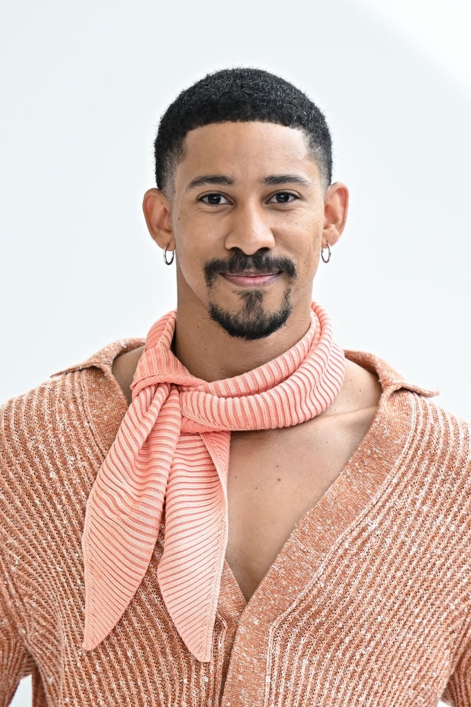 Person wearing a textured garment  and striped scarf, smiling astatine  the camera