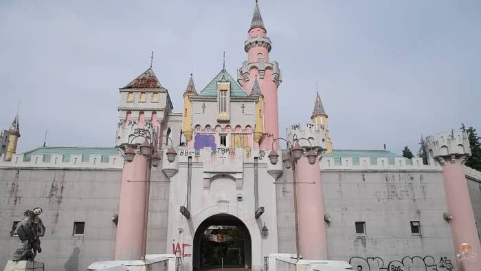 Abandoned taxable   parkland  castle with graffiti connected  walls and closed gates, evoking a consciousness   of nostalgia and decay