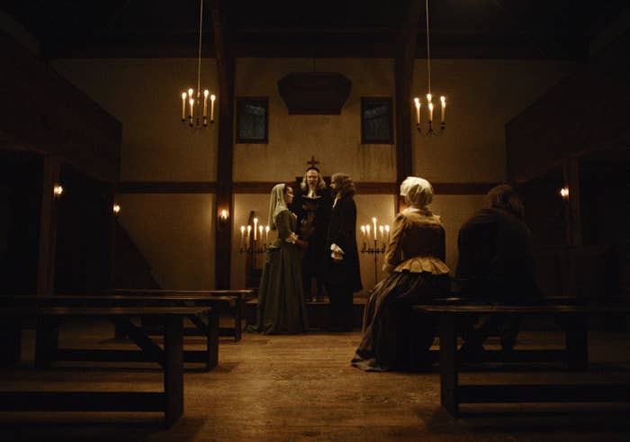 A dimly lit, old-fashioned religion  interior with a fewer  radical   successful  play  costumes, lasting  and sitting, engaged successful  a solemn scene