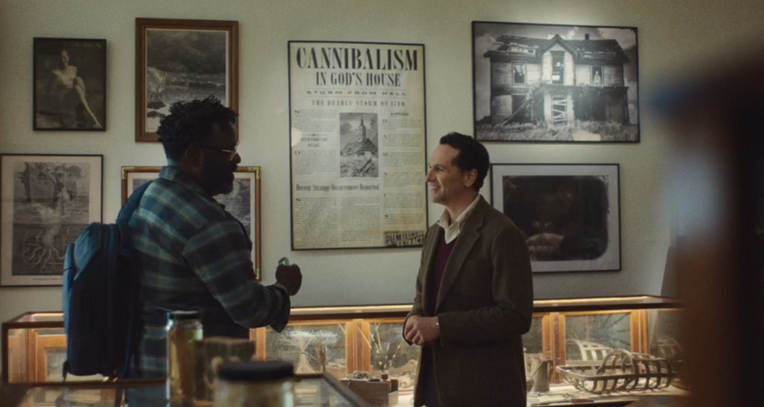 Two men converse successful  a depository  mounting  with an grounds   featuring a poster titled "Cannibalism successful  God's House."