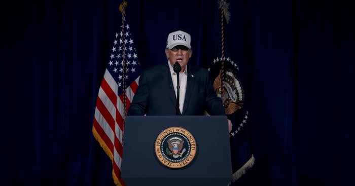 A idiosyncratic   successful  a suit   and "USA" headdress  speaks astatine  a podium with the Presidential Seal, flanked by flags