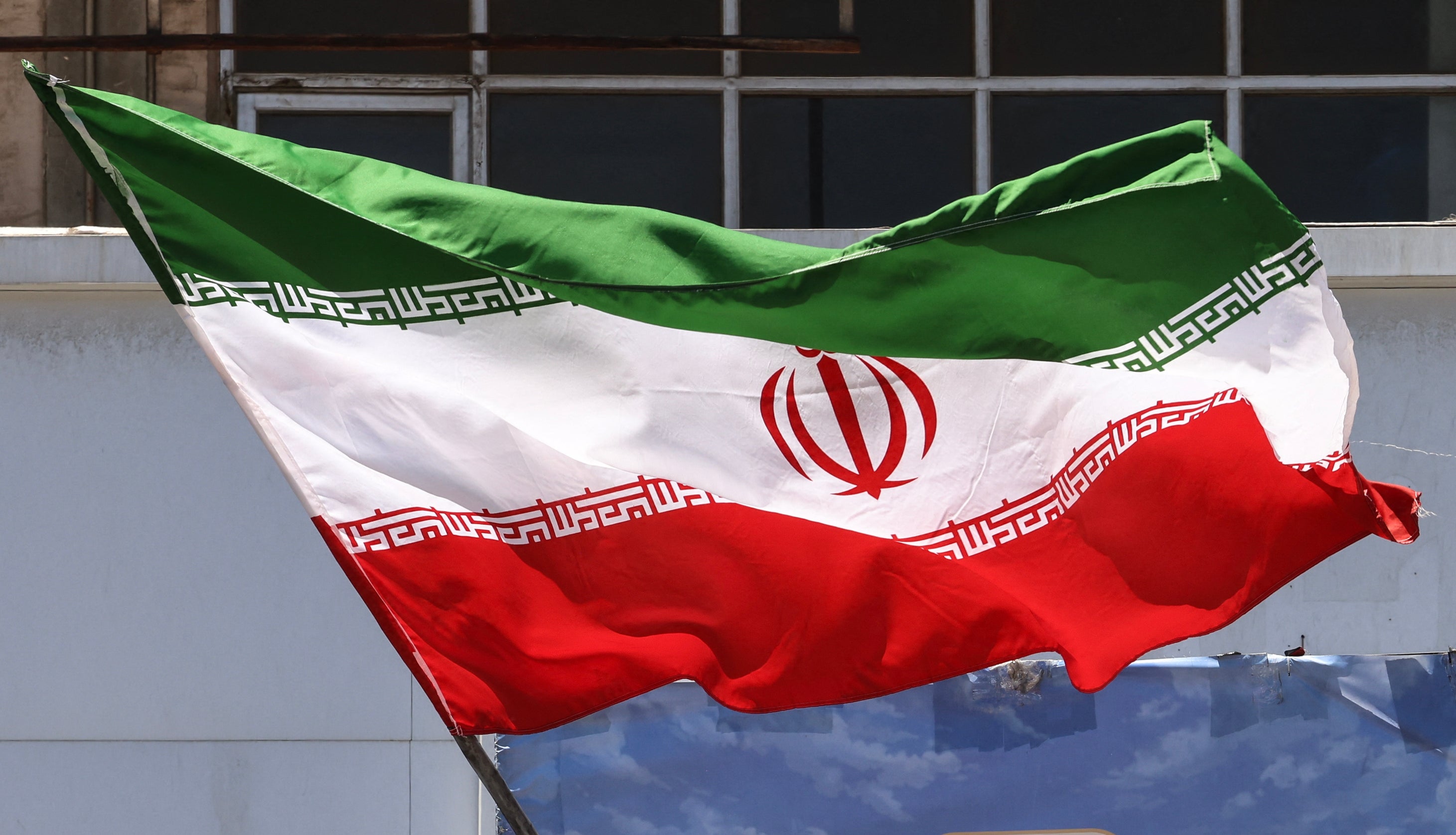 Person holding the Iranian emblem successful beforehand of a billboard with Arabic script