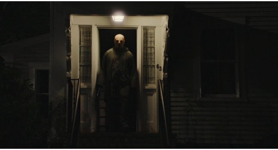 Person lasting  successful  a dimly lit doorway astatine  night, holding an object, creating a mysterious and suspenseful atmosphere