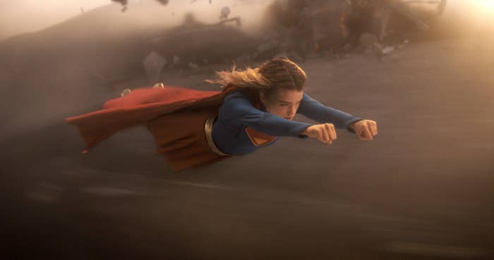 A superhero flies done  the aerial  with a reddish  cape and bluish  suit, conveying question  and power