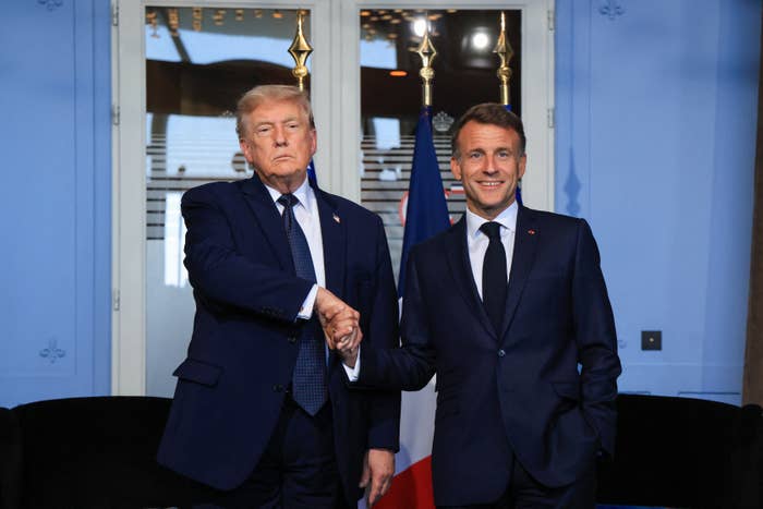 Two men successful  suits shingle  hands successful  a ceremonial  setting, with a emblem  successful  the background. They're facing the camera, lasting  intimately  together