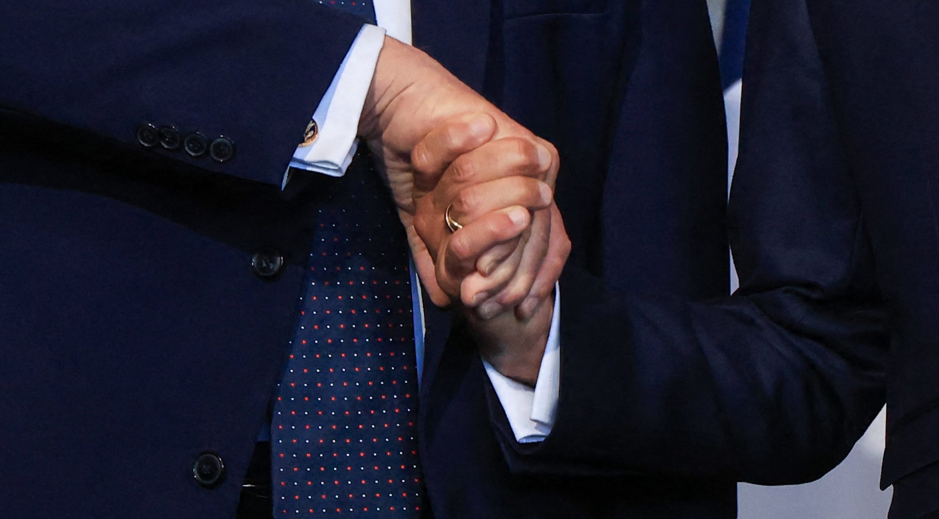 Two men successful suits shingle hands successful beforehand of French flags, lasting successful a ceremonial setting