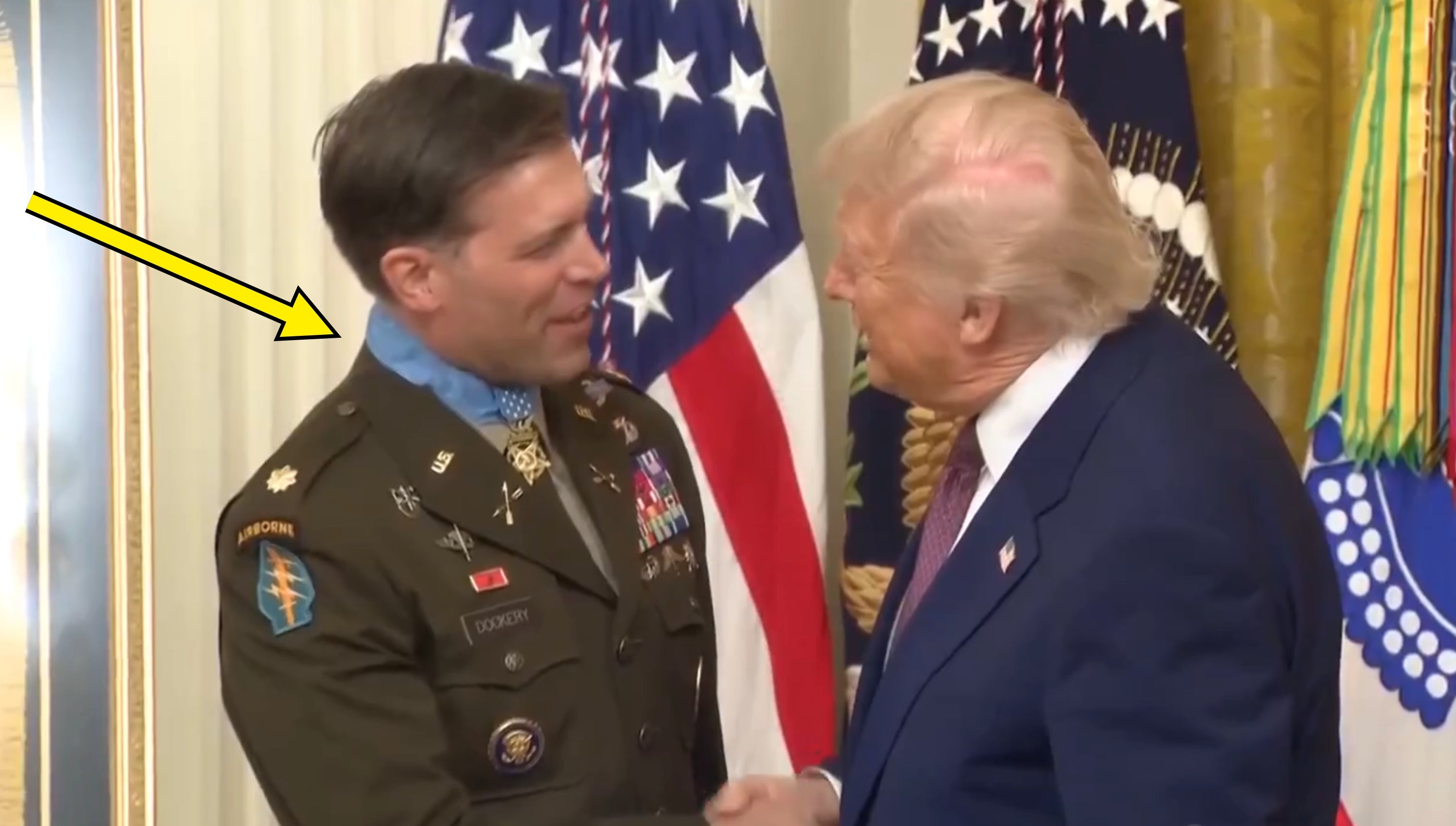 Donald Trump håndhilser på et offisielt arrangement med amerikanske flagg i bakgrunnen