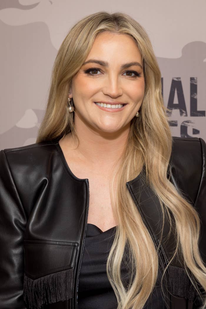 Smiling woman with long blonde hair, wearing a black leather jacket with fringe detail