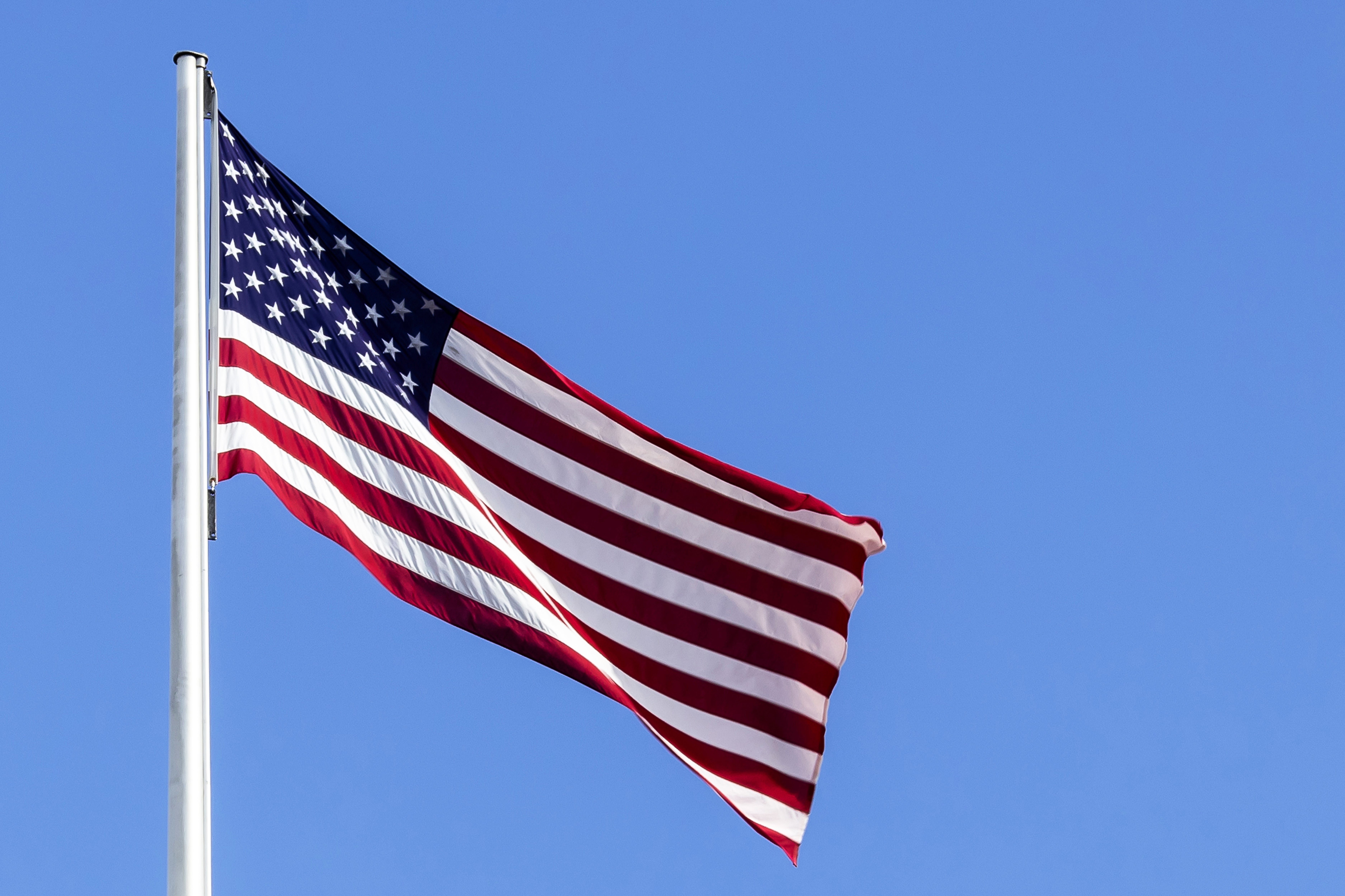 USAs flagg vaier i vinden mot en klar blå himmel