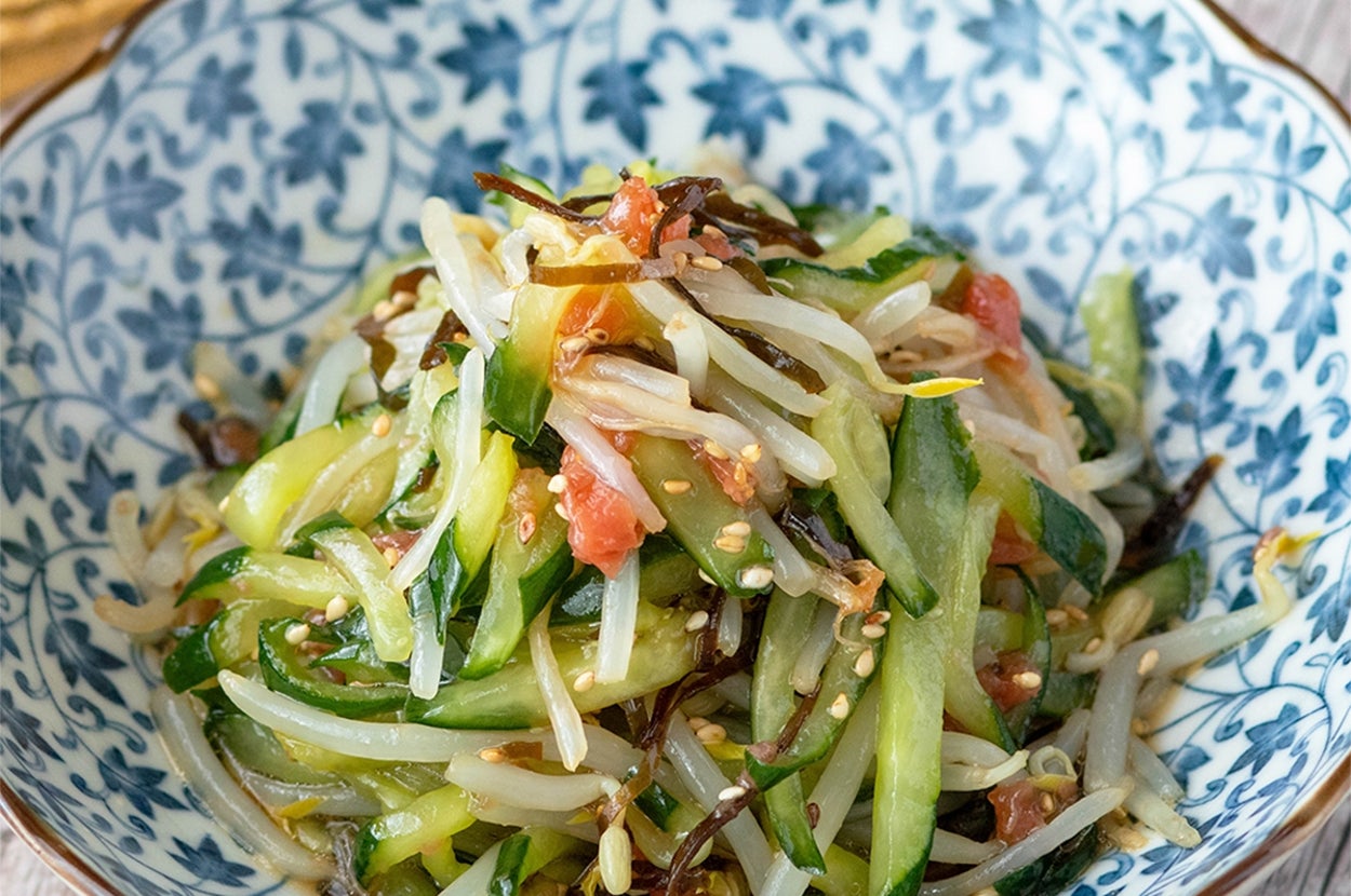 中華風の装飾的な皿に盛られた棒棒菜とキュウリのサラダ。ゴマがトッピングされている。