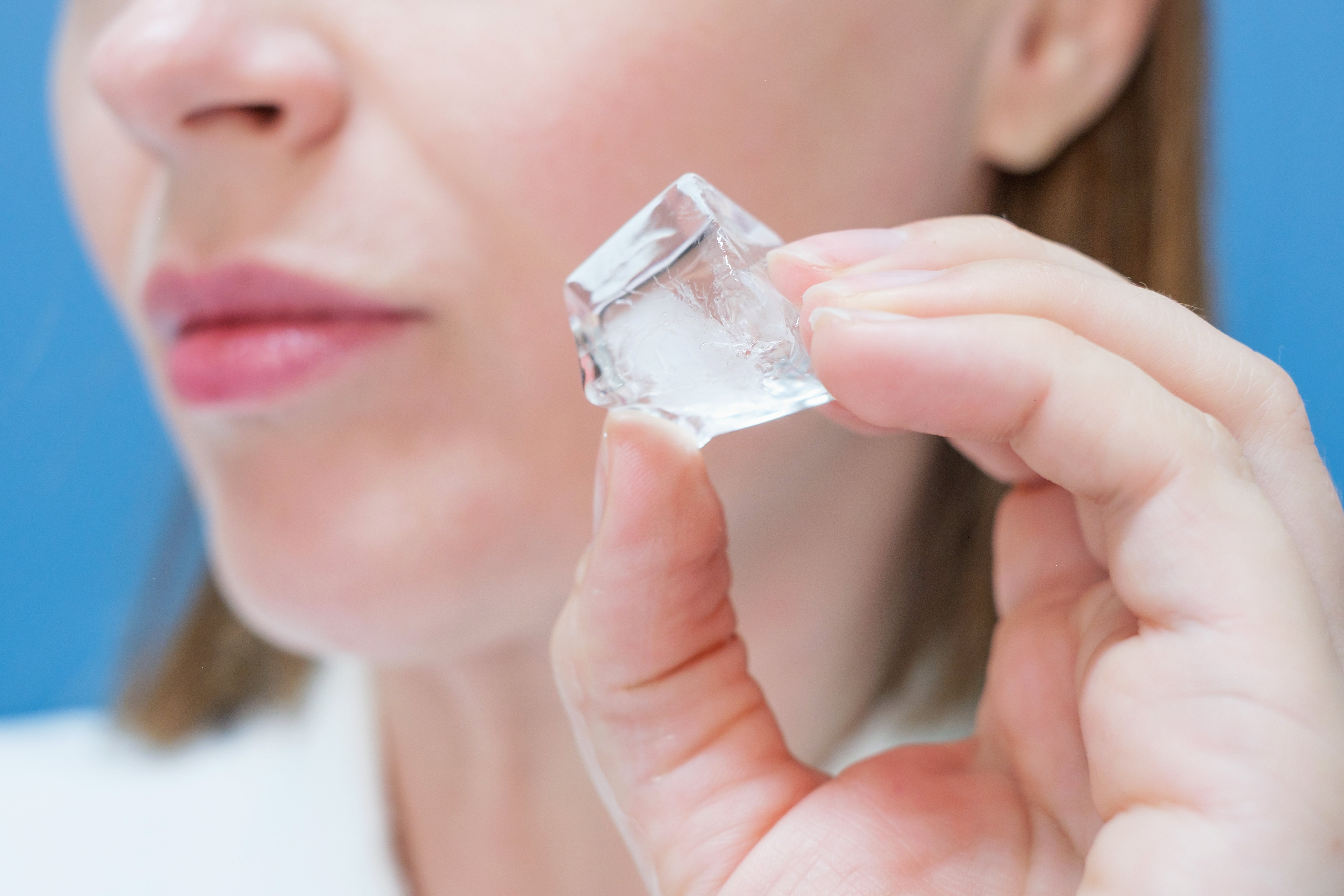 A idiosyncratic holding an crystal cube adjacent their face, lips somewhat pursed