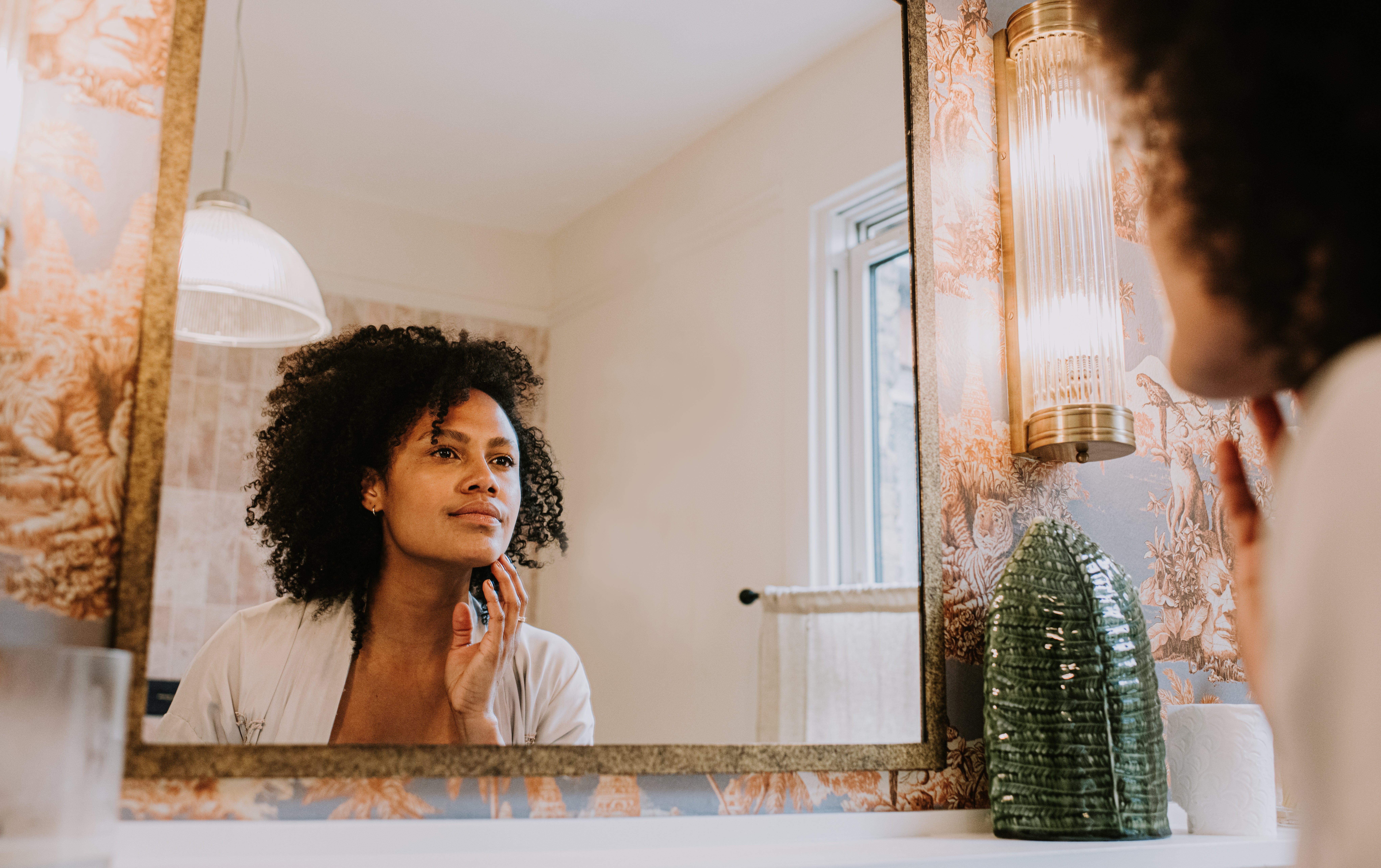 A idiosyncratic with curly hairsbreadth looking astatine themselves successful the mirror