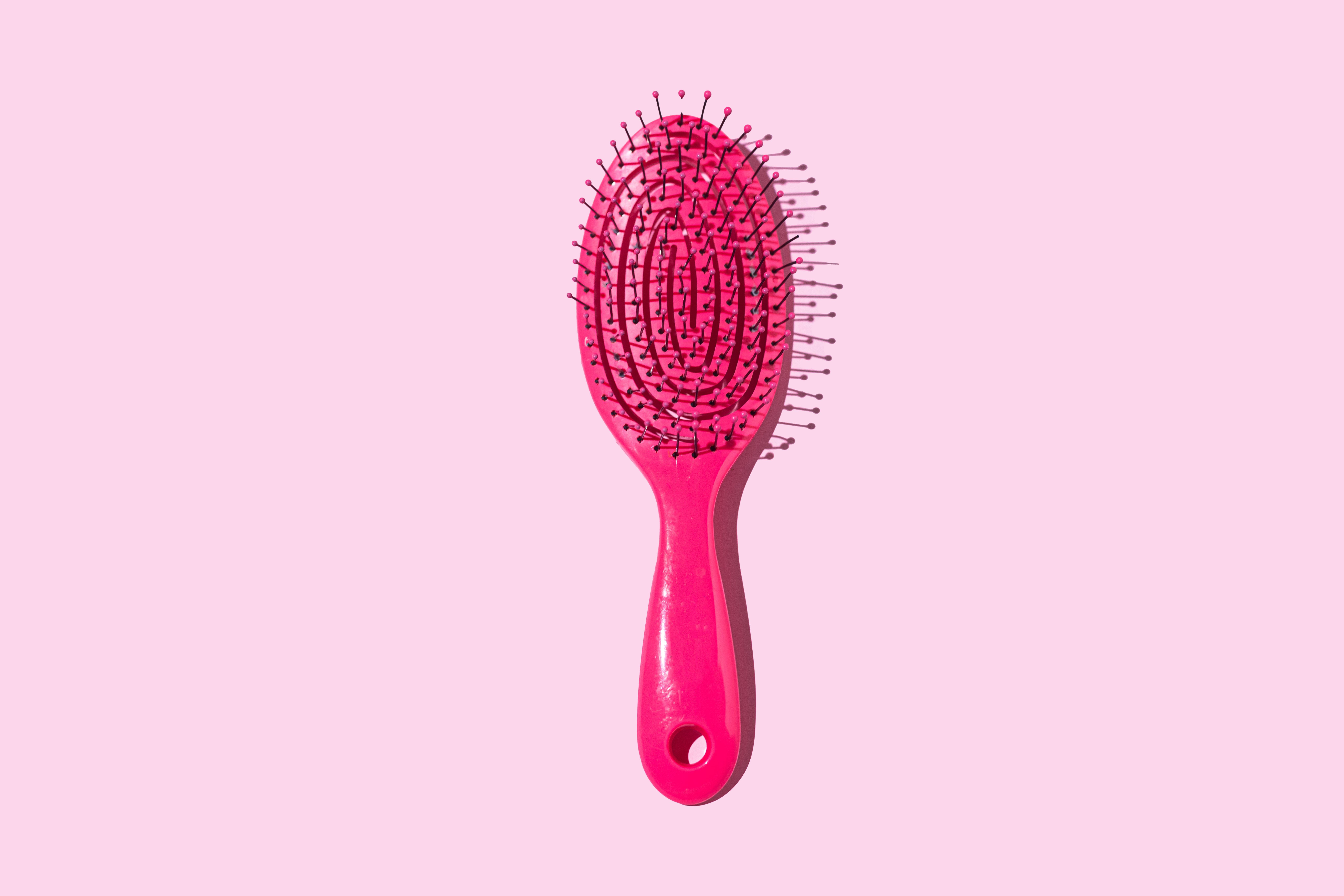 Hairbrush with bristles sticking out, placed connected a plain background
