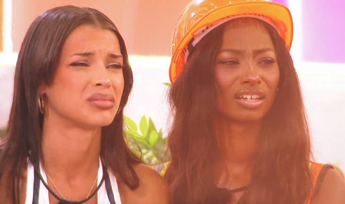 Two women, appearing perplexed, basal   together. One wears a hard   chapeau  implicit    agelong  hair, portion    the different   has hoop earrings
