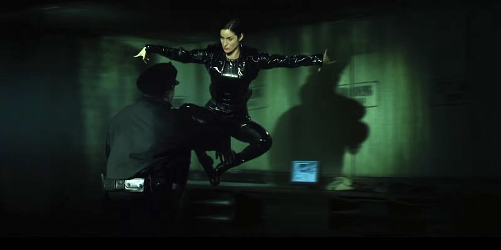 Carrie-Anne Moss successful  a sleek, achromatic  leather outfit performs a mid-air martial arts footwear   towards a constabulary  officer
