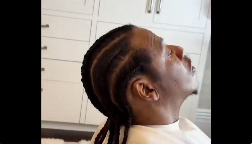 Person with braided hairstyle sits and looks upward, perchance successful a salon. Their look is calm and relaxed