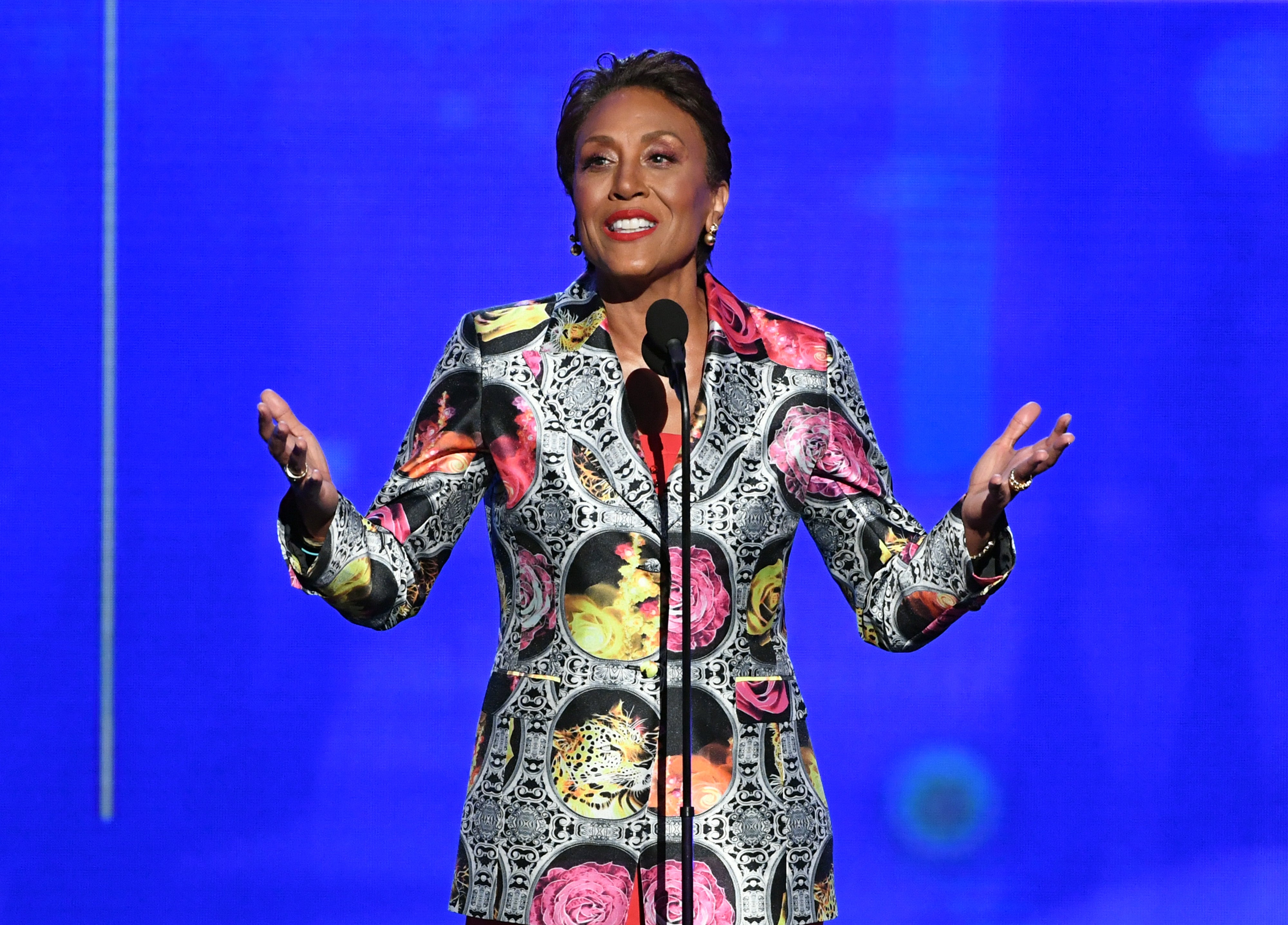 Person connected signifier successful floral-patterned suit, speaking astatine a microphone
