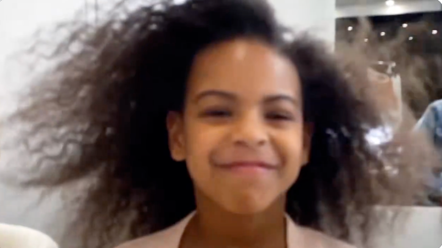 Child smiling with hairsbreadth mildly blowing, wearing a light-colored top