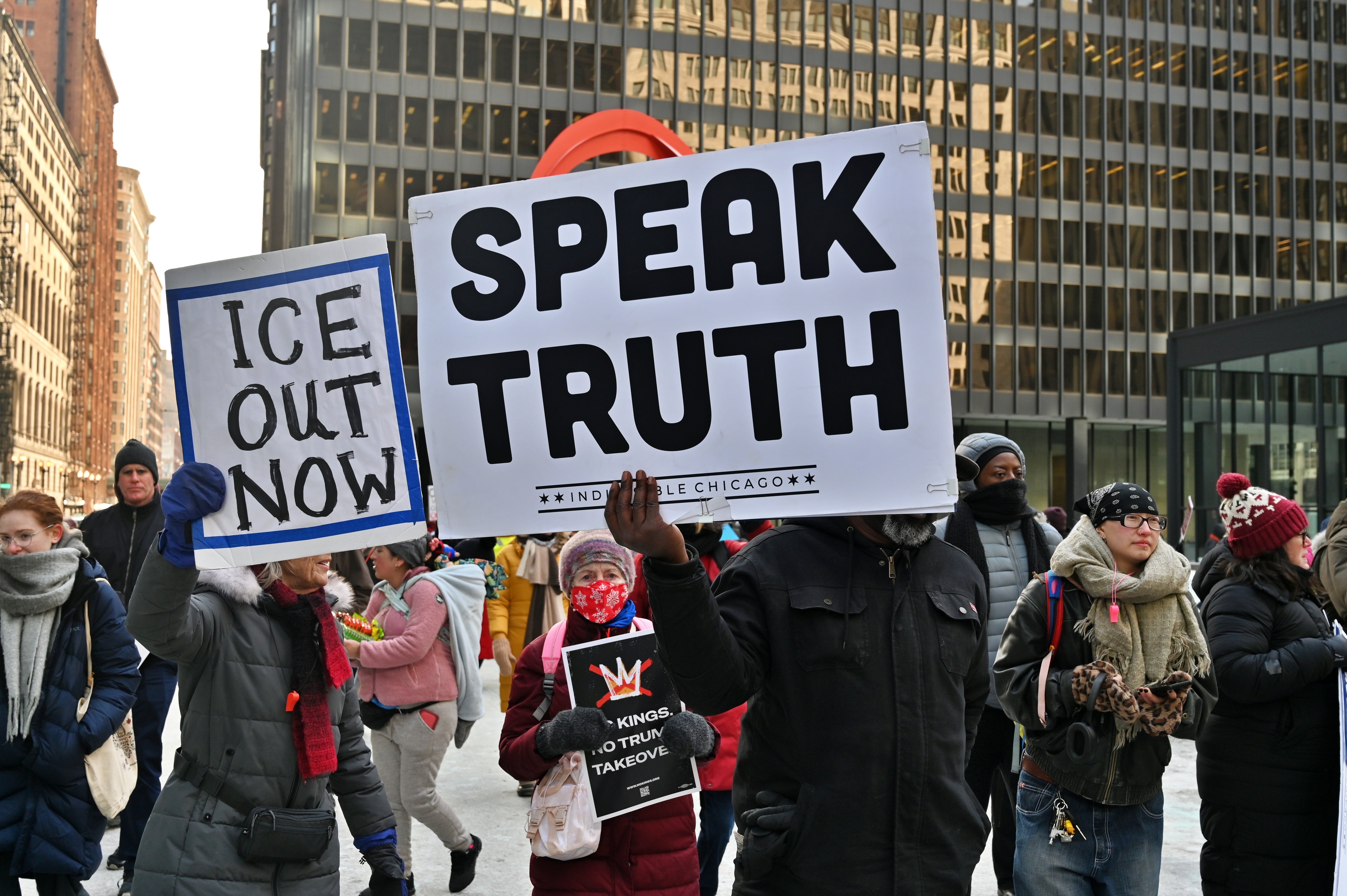 Protesters successful  wintertime  apparel  clasp  signs saying "ICE Out Now" and "Speak Truth" during a thoroughfare  march down   a metropolis  street